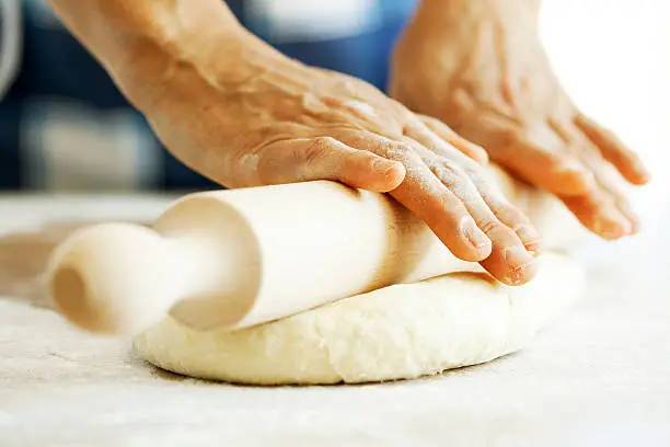 Photo of Baker with rolling pin and fresh dough