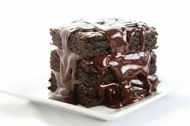 Photo of Triple chocolate fudge brownies plated on white square plate