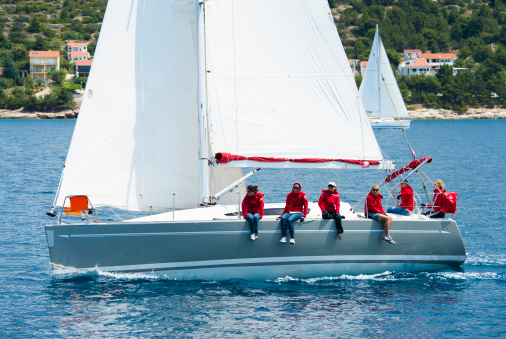 All women sailing team in red racing at regatta,  side view