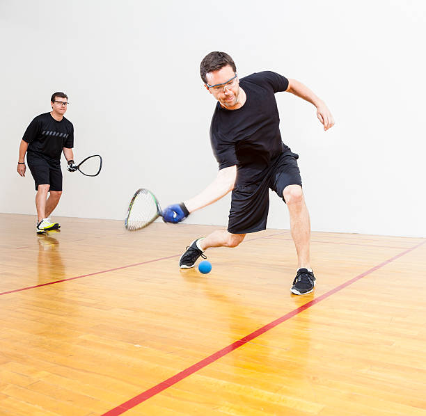 Racquetball Two men playing racquetball on court. Shot at 1/100 of a second shutter speed to create a slight blurred motion to reveal the fast motion of racquetball. racketball stock pictures, royalty-free photos & images