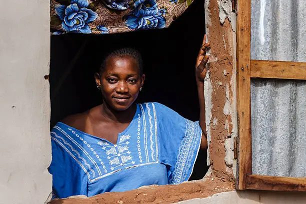 African woman posing in the window of her house