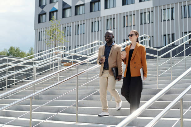 istock Two young smiling brokers or business partners walking downstairs 1713201050