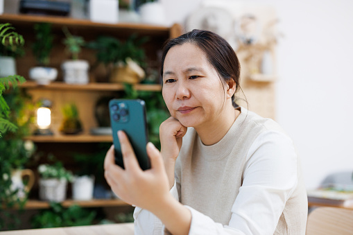 Middle aged asian women holding their phones are angry