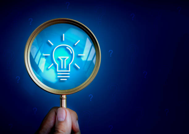 istock Business solutions, searching content and idea, creative inspiration and find keywords concepts. Lightbulb icon in magnifying glass lens in hand on dark blue background with many question mark symbol. 1713212532