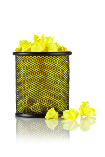 Office Trash Bin Full of Yellow Wrinkled Notes on Reflective White Background