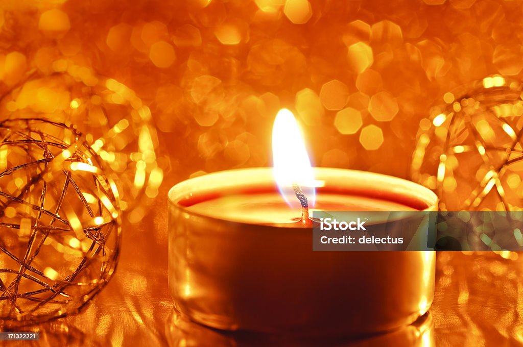 Candle on a blurred lights background Warm candlelight and Christmas decoration in front of a blurred lights background. Burning Stock Photo