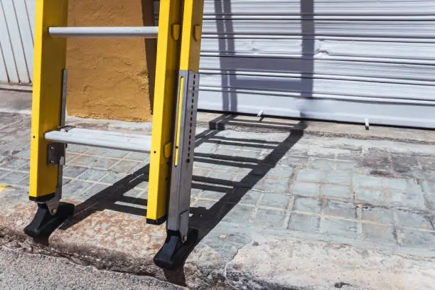 A portable ladder resting on the ground during electrical wiring repairs.