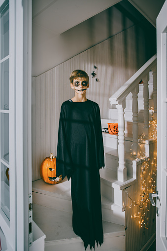 Boy dressed in Halloween costume standing on a stairs in a spooky atmosphere