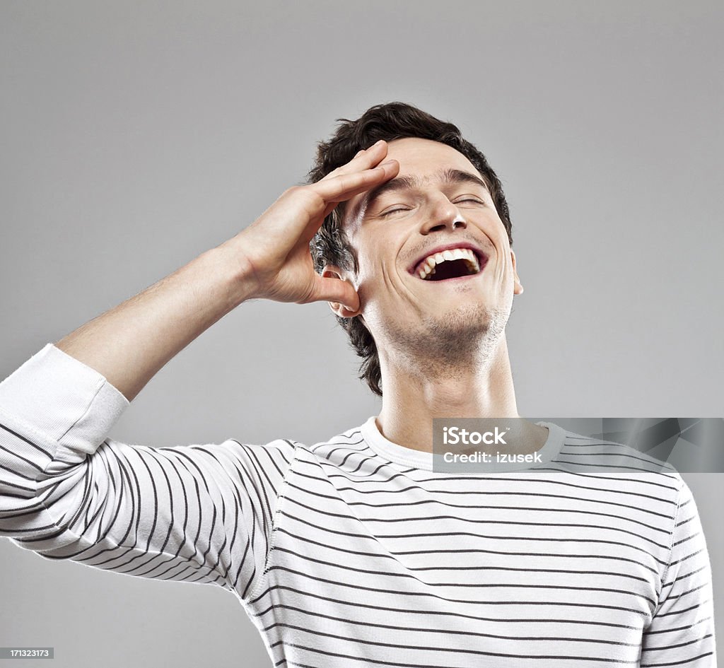 Happiness Portrait of happy young man laughing with eyes closed. Studio shot, grey background. Men Stock Photo