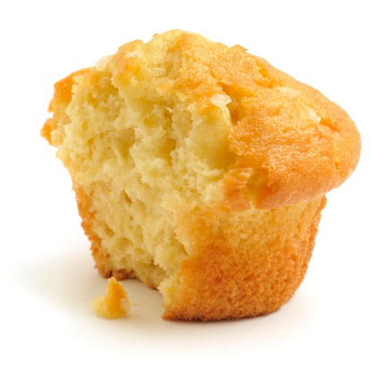 A half eaten lemon chip muffin isolated on a white background.