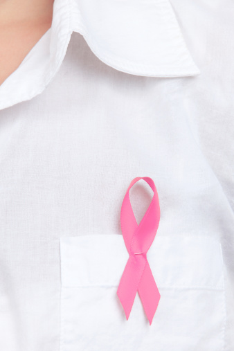 Closeup of a breast cancer awareness ribbon that is pinned to a womans white shirt. Canon 5D MarkII.