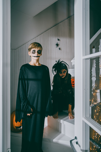 Teenagers dressed in Halloween party costumes sitting and posing on the stairs