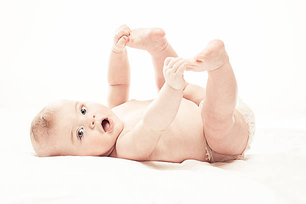 happy baby yoga Happy baby holding her feet up in the air and looking at the camera. half dressed girls pictures stock pictures, royalty-free photos & images