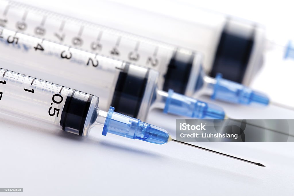 Row of medical syringes with blue lids Syringe in the white background. Syringe Stock Photo