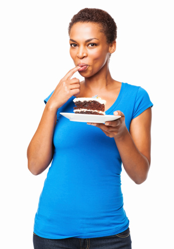 Portrait of a casual African American woman tasting pastry from her finger. Vertical shot. Isolated on white.
