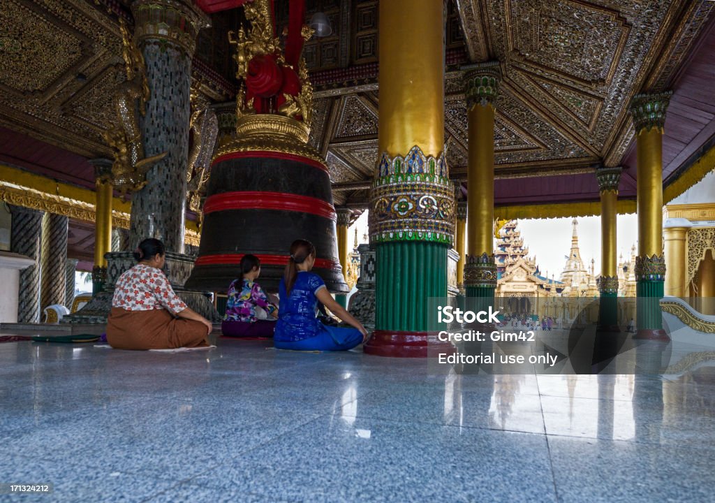 Myanmar "Yangon, Myanmar - January 9, 2012: Local faithfuls in prayer in a shrine with a big bell in the Swedagon pagoda." Asia Stock Photo