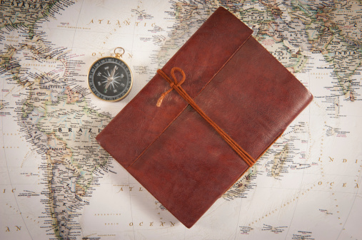 Traveller's diary and Golden compass on world map.