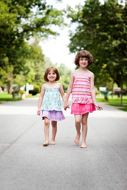 istock Two Happy Sisters Holding Hands and Walking Outside 171324921