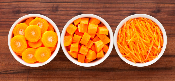 Top view of three bowls containing carrot cut in different ways