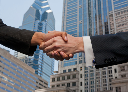 Business people handshake against an urban city background