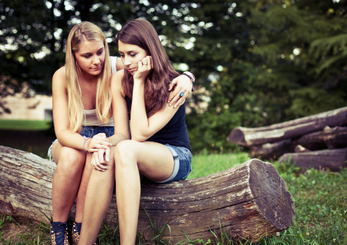 Sad teenage girls comforting each other in the park