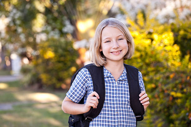 School girl walking home from school with backpack stock photo
