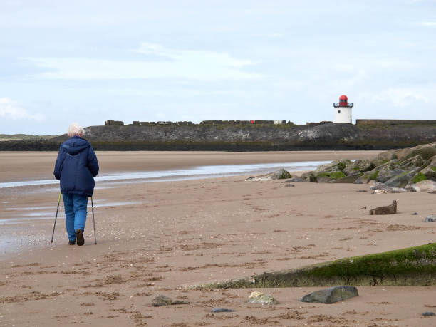 lone starszy kobieta na piaszczystej plaży - wales beach editorial people zdjęcia i obrazy z banku zdjęć