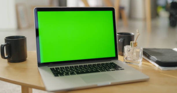 istock Laptop Computer with Mock Up Green Screen Display Standing on a Table in Cozy Living Room. Stylish Modern Bright Home Office Studio with Two Tea or Coffee Cups on the Table. Static Footage 1713267922