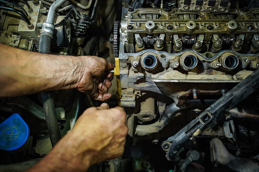 Close up shot of Male hands repairing automobile vehicle engine.