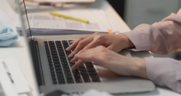 istock Close Up Footage of a Data Analyst's Hands Typing Emails on a Laptop Computer Keyboard, Conducting In-Depth Data Analysis of Printed Documents, Extracting Insights and Generating Reports for Company 1713271087