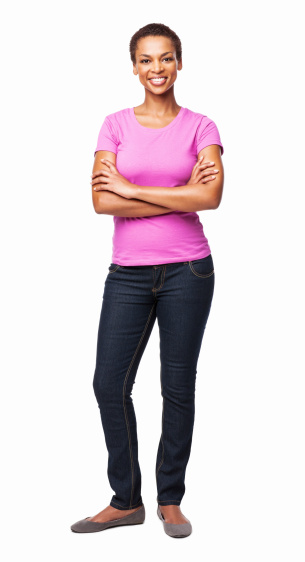 Full length portrait of a casual African American woman in a pink t-shirt smiling with arms crossed. Vertical shot. Isolated on white.