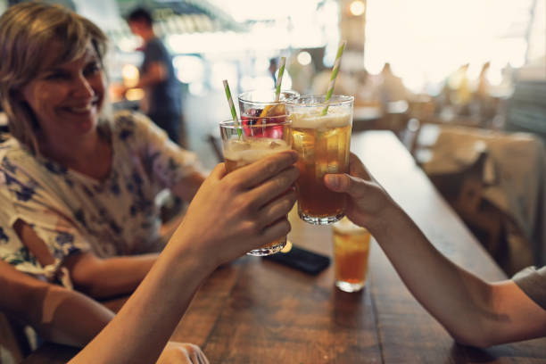 Mother and teenage kids drinking lemonades. They are making a toast .\nShot with Canon R5