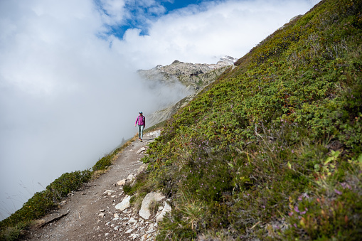 A healthy woman hiking along a trail in the mountains in France on a beautiful morning. Things to do outdoors in Chamonix while on holiday in the summer