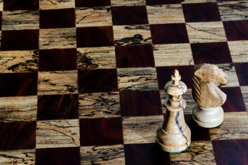 Wooden chess pieces on a checkered board.