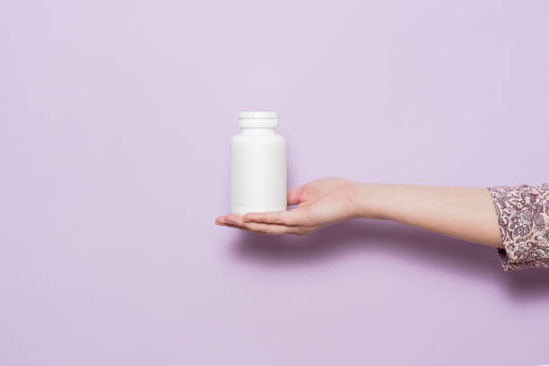 istock White plastic bottle in female hand. Packaging for pills, capsules or supplements. 1713283428