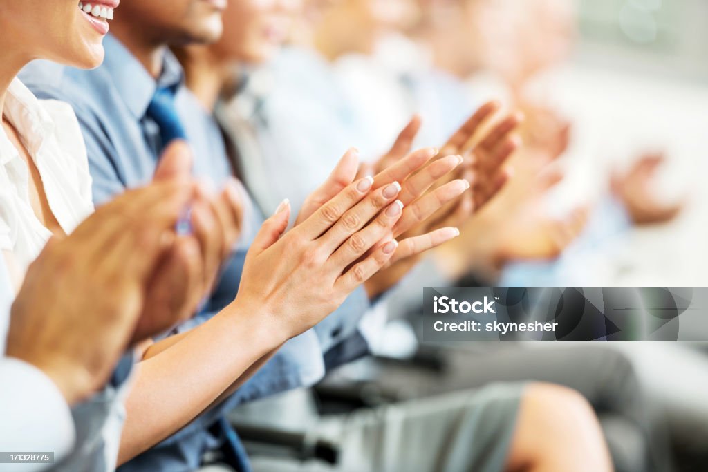 Group of businesspeople sitting in a line and applauding. Group of cheerful businesspeople sitting in a row on a presentation and clapping. Clapping Stock Photo