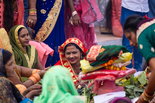 Ghaziabad, Uttar Pradesh, India - October 2022: Chhath Puja, Indian hindu female devotee performing rituals of chhath puja to worship lord sun during sunset.