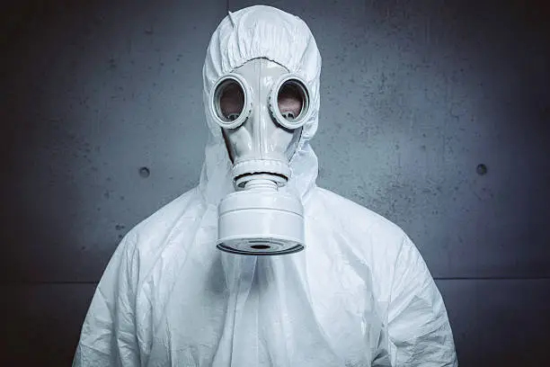 Man in protective workwear and gas mask, scared for nuclear alert.