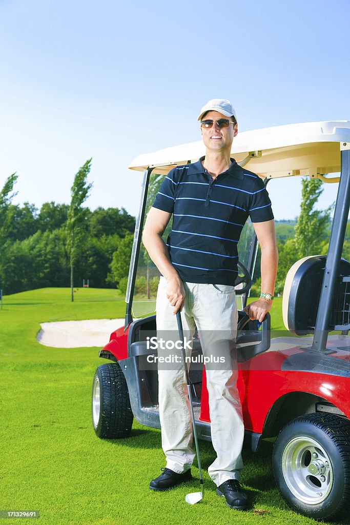 man standing next to a golf cart Golf Stock Photo