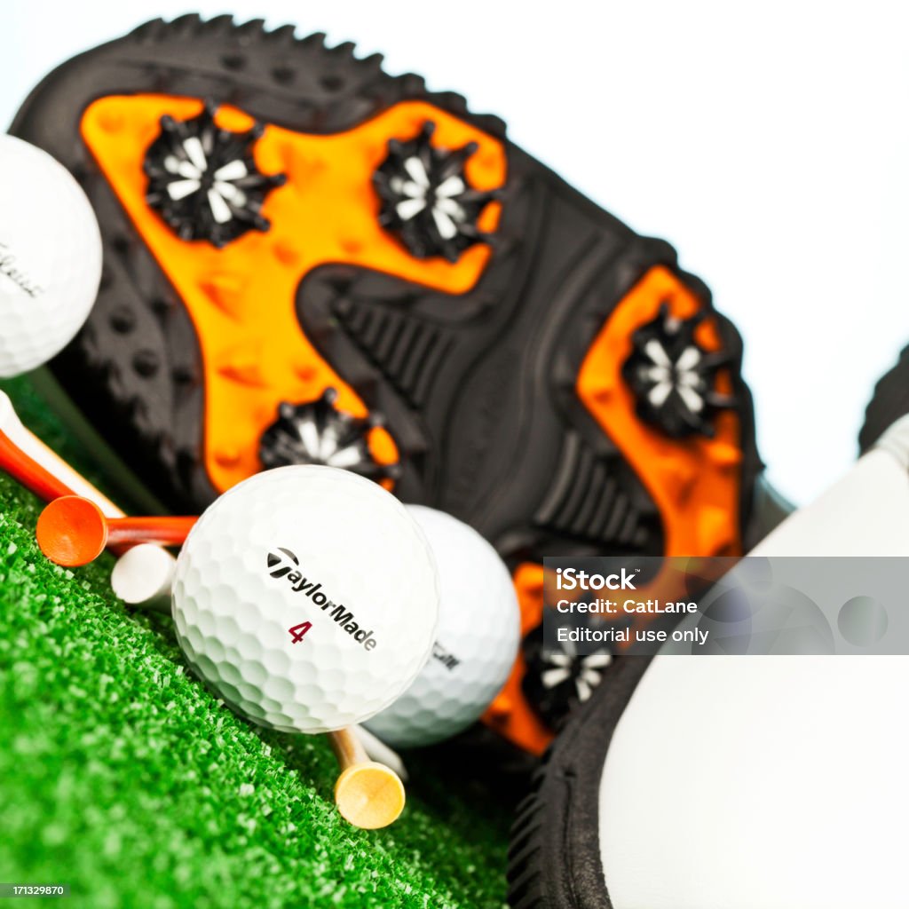 Golf Necessities "Suffolk, Virginia, USA - August 19, 2012: A square format studio shot of a brand new pair of men's FootJoy brand golf shoes showing the underside of the shoe, a Taylor Made golf ball, Titleist golf ball and a Bridgestone golf ball with some colored tees. This style of golf shoe is from the Contour Series." Beauty Stock Photo