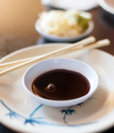 Bowl of soy sauce with chopsticks on table