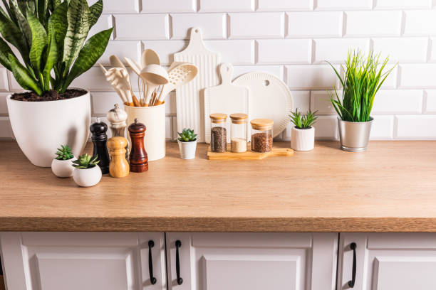 istock Beautiful kitchen background of a modern countertop with a set of various kitchen utensils, green plants in pots. Eco style. natural materials. 1713304850