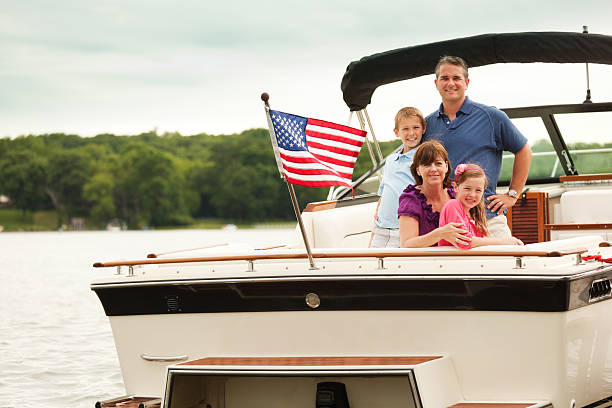 Happy, Smiling American Family Boating on Midwest Lake with Motorboat Happy, smiling American family boating on a lake motorboat, Midwest, USA. Caucasian affluent parents and children—father, mother, boy, and girl—pose for a portrait on their motorized speed boat. An American flag waves at back, celebrating a Fourth of July or Memorial Day patriotic summer vacation water sport outting. boat on lake stock pictures, royalty-free photos & images