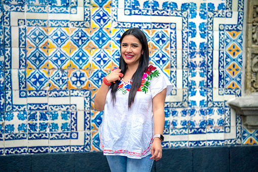 Happy young mexican woman tourist in front of Sanborns restaurant wall in downtown Mexico City