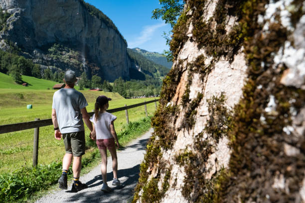 A father and daughter enjoy a walk through the beautiful village of Lauterbrunnen in Switzerland. Family exploring the small villages in and around Europe while on vacation