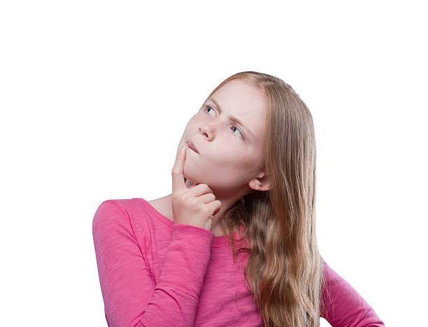 Curious young girl looking up "Questioning pre-adolescent girl, isolated against a white background" blond girl making a face confusion stock pictures, royalty-free photos & images