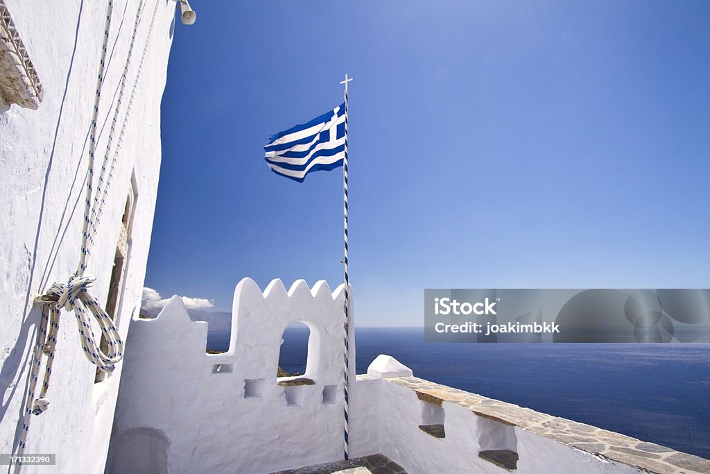 Greek flag waving in the sky Greek flag waving in the sky at the famous monastery of Monastery of Hozoviotissa in Amorgos. Greek Flag Stock Photo