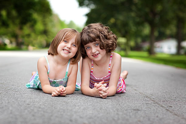 istock Two Happy Sisters Lying Down On Quiet Street 171332457