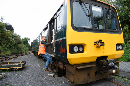 A train driver getting into the locomotive at Tarka Valley Railway, Devon UK.