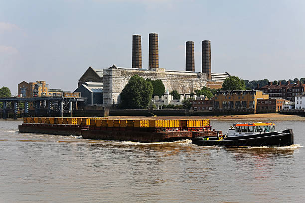 A boat pushes a barge with a crane on the river, dedicated to collecting aquatic debris